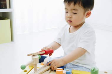 Asyalı çocuk tahta oyuncaklar oynuyor.