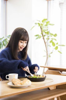 Güzel genç bir kadın Japon restoranında öğle yemeği yiyor.