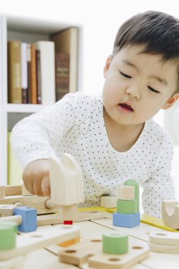 Küçük Asyalı kız ahşap oyuncaklarla oynuyor.