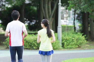 Sportif genç Asyalı çift parkta koşuyor.