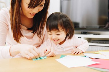 Anne ve kızı kağıt oyuncaklar yapıyor.