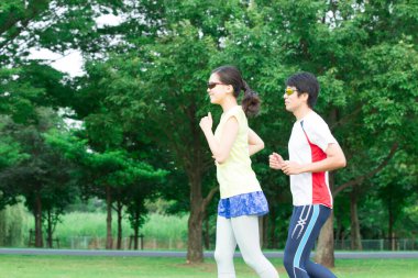 Sportif genç Asyalı çift parkta koşuyor.