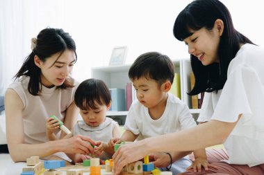 Çocuklarla evde oynayan gülümseyen Asyalı anneler