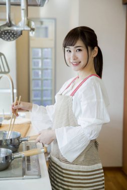 Güzel Japon kadın mutfakta yemek pişiriyor.