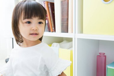 Küçük tatlı Çinli kızın portresi. Odadan dışarı bakıyor. 