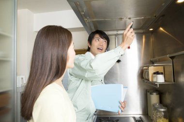 Asyalı kadın ve erkek teknisyen mutfak aletlerini kontrol ediyor.