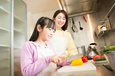 Genç anne ve kız mutfakta birlikte yemek hazırlıyorlar.