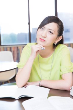 Masasında kitapları olan genç bir kadın. 