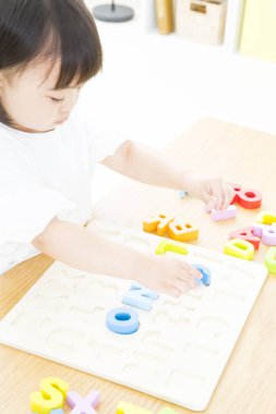 Küçük çocuk anaokulunda renkli plastik harflerle oynuyor..