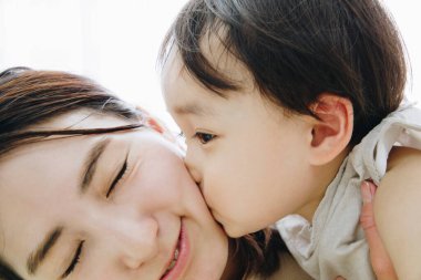 Küçük oğluyla öpüşen genç bir kadın.