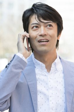 Genç Asyalı işadamı şehirde akıllı telefon kullanıyor.