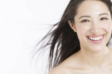 Uçan rüzgâr saçlı mutlu genç kadın beyaz arka planda izole edilmiş.