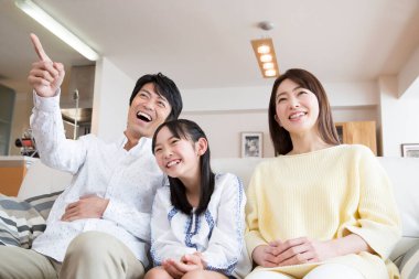 Mutlu bir aile kanepede oturup birlikte gülüyor.