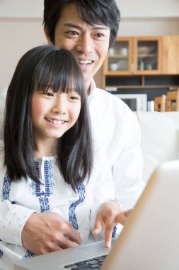 Evde dizüstü bilgisayar kullanan mutlu bir Asyalı aile.