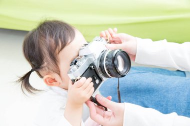 Bebekli genç anne kamerayla oynuyor.