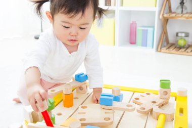 Küçük Çinli çocuk tahta oyuncak bloklarıyla oynuyor.