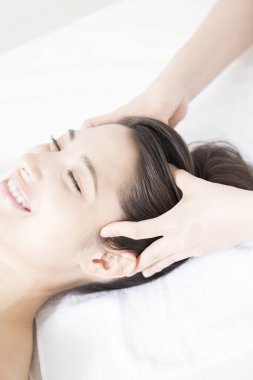 Genç ve güzel Japon kadın spa merkezinde yüz masajından zevk alıyor..