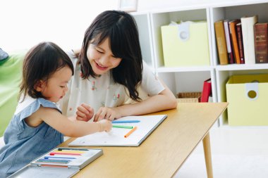 Küçük Asyalı kız ve anne evde resim çiziyor.
