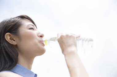 Asyalı kadın açık havada su içiyor. 
