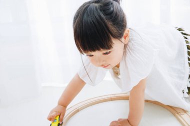 Küçük tatlı Japon kız oturma odasında oyuncaklarla oynuyor.