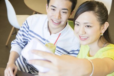 Asyalı çift kahve molasında selfie çekiyor. 