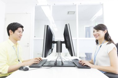 Genç Asyalı iş çifti ofiste bilgisayar üzerinde çalışıyor.