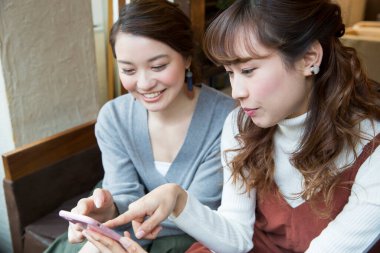 Kafede cep telefonu kullanan genç kadınlar