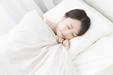 Güzel Asyalı kadın, sabahları yatakta uyuyor.
