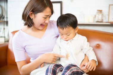 Kadının biri oğlanın lekeli gömleğini gösteriyor.