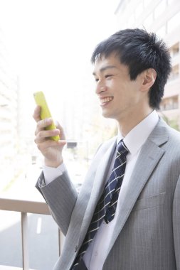 Sokakta akıllı telefonu olan takım elbiseli genç bir adam. 