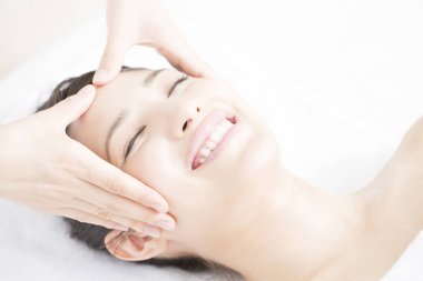 Genç ve güzel Japon kadın spa merkezinde yüz masajından zevk alıyor..