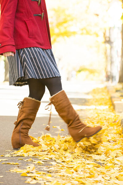 Девушка с желтыми листьями клена в осеннем парке.