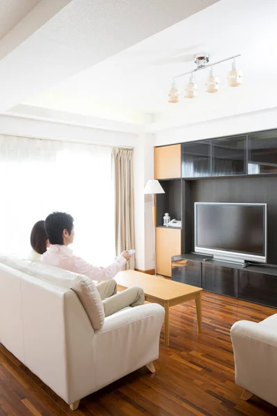 asian young woman relaxing on sofa in living room watching tv