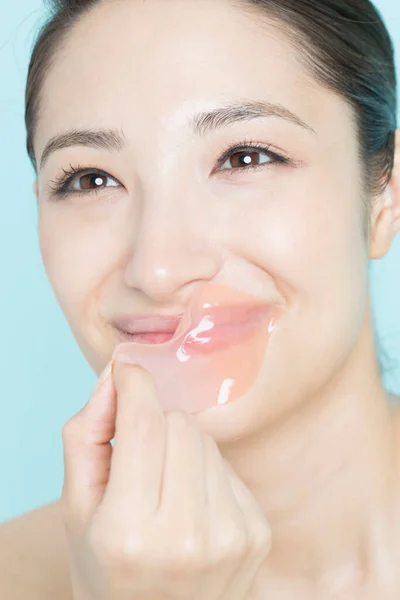 年轻女人从嘴唇上摘除粉红的水凝胶斑块 化妆品和皮肤护理 美容肌肤及防皱护理 — 图库照片