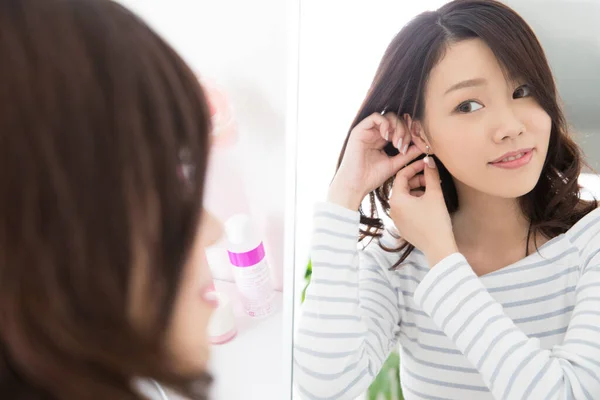 美丽的亚洲女人在镜子前调整耳环 — 图库照片