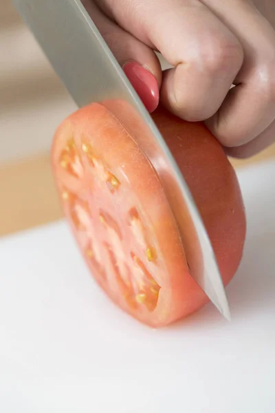 キッチンテーブルに赤いトマトを切った女性 — ストック写真
