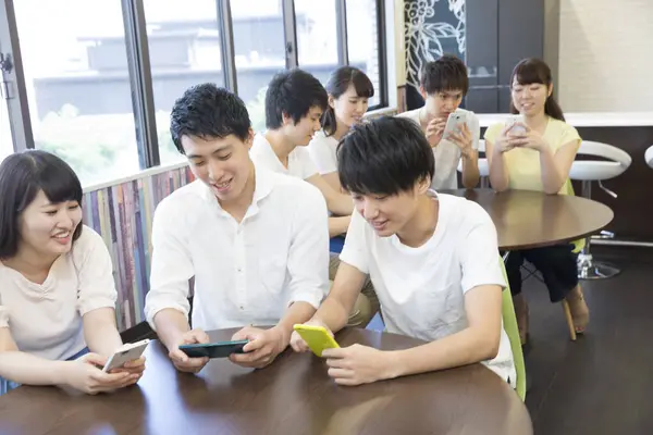 Nuoret Aasialaiset Opiskelijat Käyttävät Älypuhelimia Luokkahuoneessa — kuvapankkivalokuva