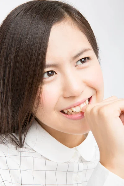 白い背景に釘を噛むことを考える美しい日本の女性のスタジオショット — ストック写真