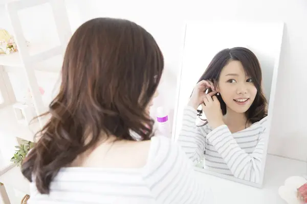 鏡の前でイヤリングを調整する美しいアジアの女性 — ストック写真