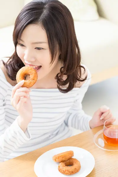 美丽的亚洲女人吃着美味的甜甜圈 — 图库照片