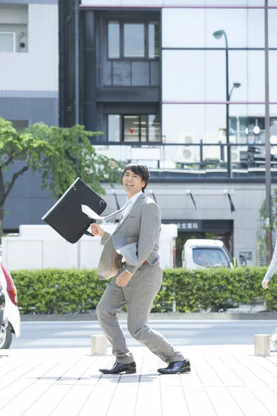 handsome professional asian businessman with briefcase  on street