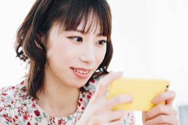 Akıllı telefon kullanan gülümseyen Asyalı genç kadının portresi 