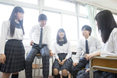 Gülümseyen öğrenciler sınıf pencerelerinin yanında toplanıyor