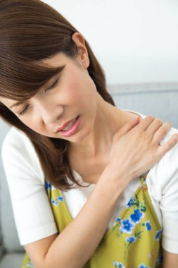 Evde omuz ağrısı çeken bir kadın.