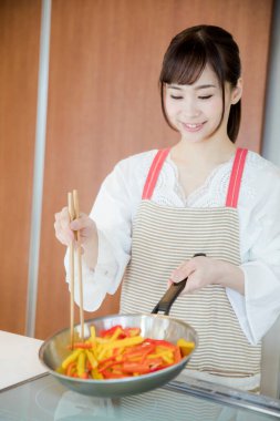 Genç Japon kadının portresi mutfakta yemek hazırlıyor. 