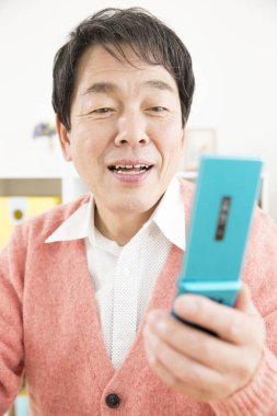 Üst düzey Asyalı adam evde cep telefonu kullanıyor.