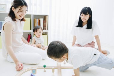 Neşeli Asyalı anneler ve çocuklar oturma odasında oynuyor.