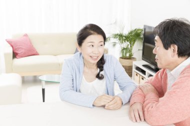 Asyalı son sınıf öğrencisi kadın evde kocasıyla konuşuyor. 