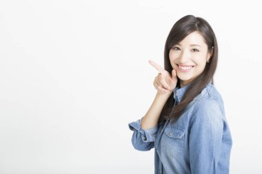 Beyaz arka planı işaret eden genç bir kadın.