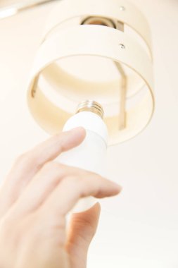 Avizedeki ampulü değiştiren elektrikçinin eli. 